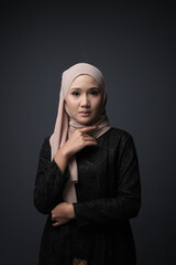 Portrait of a female  wearing a hijab, a form of lifestyle garments for Muslim women, isolated on a dark background. Eid festive and hijab fashion concept