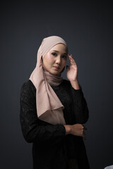 Portrait of a female  wearing a hijab, a form of lifestyle garments for Muslim women, isolated on a dark background. Eid festive and hijab fashion concept