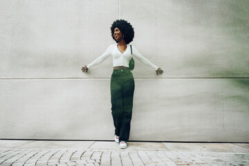 Black woman with afro hair posing in front of a gray concrete wall