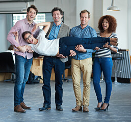 Colleagues having fun, playing and feeling playful while carrying fun coworker, being silly and...