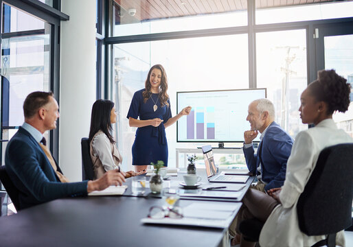 Businesswoman analysis giving a statistic presentation in a diverse boardroom. Professional business female presenting to her work colleagues in the conference room, explaining graphics for growth. - Powered by Adobe