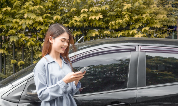 asian Beautiful young woman using smartphone near car with copy space