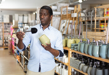 Portrait of African American shopper choosing bathroom accessories in home decor shop. Home...