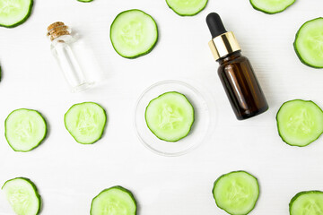 Fototapeta na wymiar Serum and tonic in glass containers on a white background with cucumber slices, top view. Moisturizer for face and skin, treatment and body care.