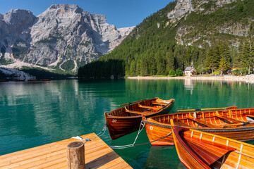 Fototapeta premium Amazing Sunrise view of Lago di Braies (Pragser Wildsee) with Wooden boats, one of the most beautiful lake in South Tirol, Dolomites mountains, Italy. Popular tourist attraction.