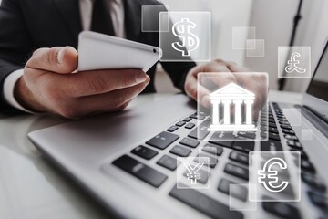 Businessman using laptop computer with central banking icon and currency for trading forex money transfer concept.