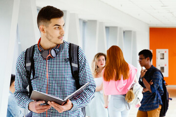 The student stands in the corridor of the educational building and looks at the book