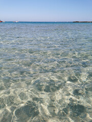 Fig Tree Bay beach, crystal clear water, white sand at the bottom, small island off the coast.