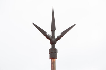 Lightning rod with three sharp metallic spikes mounted on a copper pole, designed for efficient lightning protection. Captured against a bright sky background, lightning protection