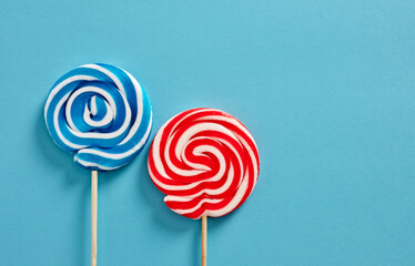Colorful swirl round candy lollipops on blue background. - obrazy, fototapety, plakaty