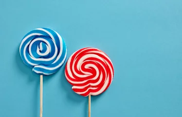 Gordijnen Colorful swirl round candy lollipops on blue background. © Cagkan
