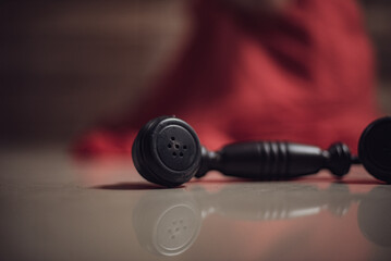 Closeup of a black telephone receiver in front of a woman in red gown