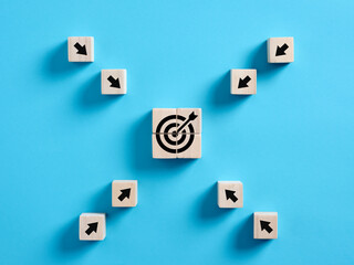 Arrows pointing towards the target icon on wooden cube. Achieving goals or aiming and focusing on the target in business