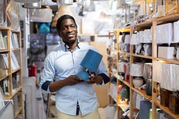 Man is choosing new table lamp for her home in the store