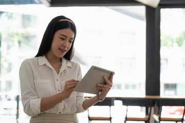 Obraz premium Young asian girl using digital tablet stand at home office