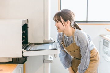 Obraz na płótnie Canvas 電子レンジ・オーブンを使う女性（笑顔） 