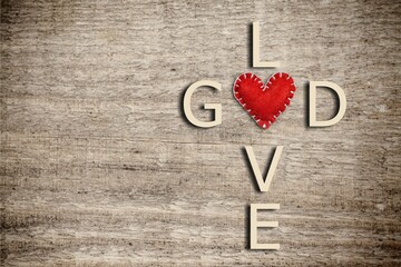 God and love words written in the shape of a religious cross with red heart on background