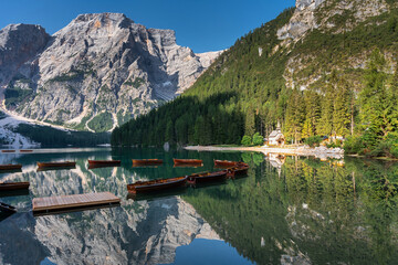 Fototapeta premium Amazing Sunrise view of Lago di Braies (Pragser Wildsee) with Wooden boats, one of the most beautiful lake in South Tirol, Dolomites mountains, Italy. Popular tourist attraction.