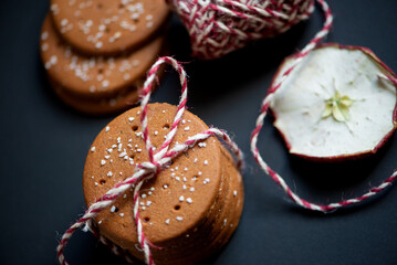 a stack of round-shaped gingerbread cookies tied with a thread of red woolen yarn on a dark background