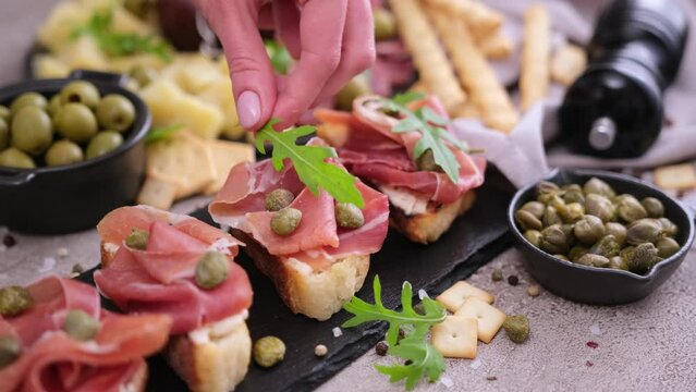 Making bruschetta with prosciutto or jamon ham at domestic kitchen