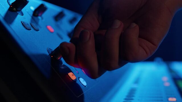 Close-up of the hands of a male DJ who turns the sound control on the console