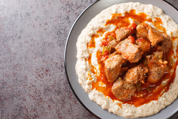 Turkish Hunkar Begendi meat on a bed of baked eggplant with bechamel closeup in the plate on the table. Horizontal top view from above