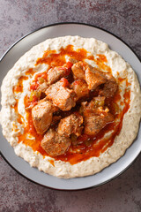 Hunkar Begendi Meat Stew over Eggplant Sauce closeup in the plate on the table. Vertical top view...