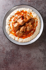 Sultan’s delight Hunkar begendi is an Ottaman dish that consists of a lamb stew served over an eggplant bechamel sauce closeup in the plate on the table. Vertical top view from above