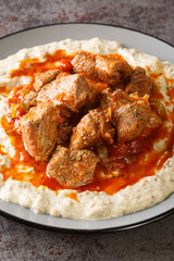 Sultan’s delight Hunkar begendi is an Ottaman dish that consists of a lamb stew served over an eggplant bechamel sauce closeup in the plate on the table. Vertical
