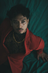 man wearing red blazer and gold chain captured from high angle. 