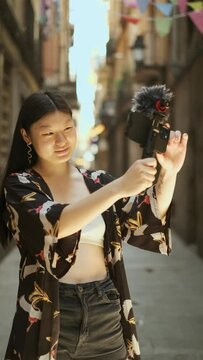 Young female blogger recording video with a mobile phone outdoors on the street. Slow motion. Technology and social media concept.