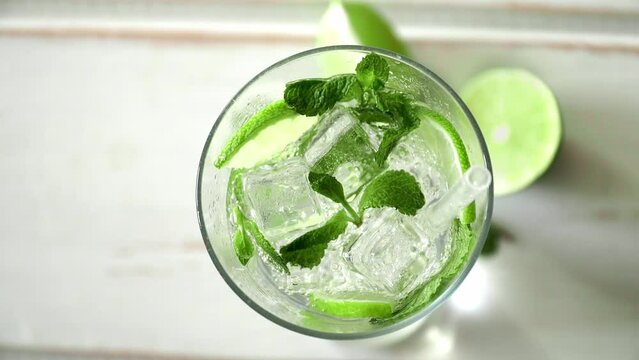 Top view of soda water in glass with fresh slices lime, mint and ice on table. Mojito cocktail. Summer drink, sparkling water, carbonated