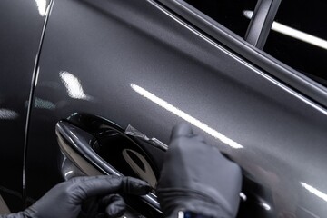 employee of the car detailing studio protects the car body with a colorless protective film