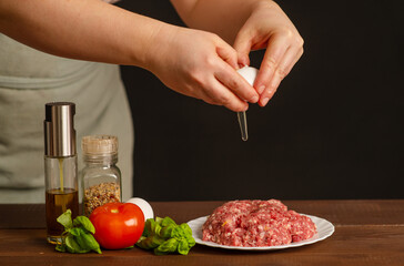 The cook breaks an egg into a fresh mince for a burger. Cooking a burger. Frozen egg movement in flight