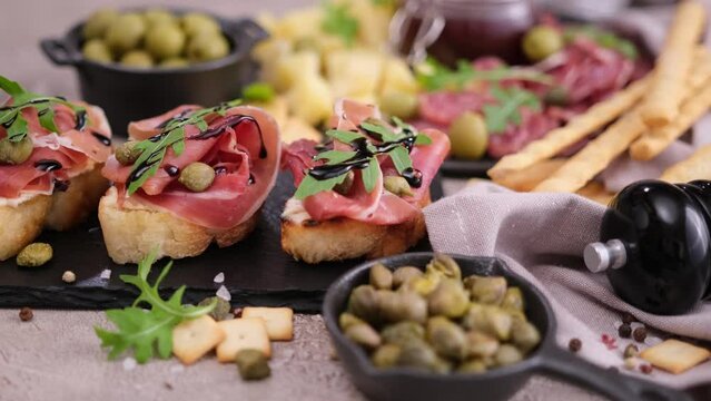 Making bruschetta with prosciutto or jamon ham at domestic kitchen