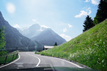 Asphalt road in Alps mountains at hills and mountain village background. Road trip concept.