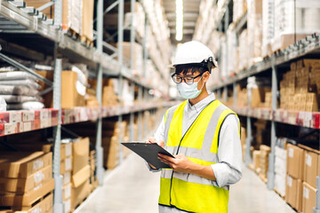 Portrait asian engineer man shipping order detail on clipboard check goods and supplies on shelves with goods background inventory in factory warehouse.logistic industry and business export