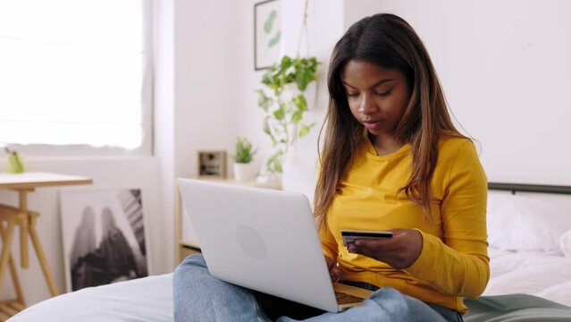 Young latin woman shopping online. Teenage girl making online payment with credit card on laptop. High quality 4k footage