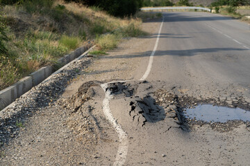 Deep hole in the road. Deformed asphalt surface with potholes melts from heat due to heavy...