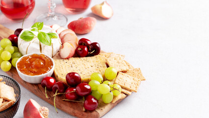 Fototapeta na wymiar Healthy mediterranean cheese and fruits board with rose wine on light background