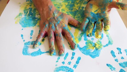 Hands of adult man covered with blue and yellow paint for artistic handprint for Ukraine solidarity