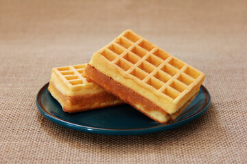 sweet fluted belgian waffles in a blue plate on a brown background