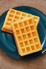 sweet fluted belgian waffles in a blue plate on a brown background