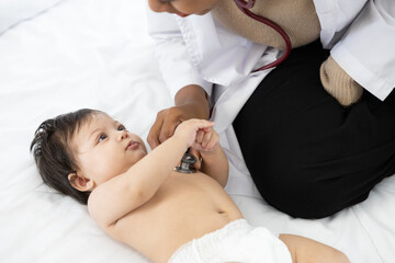 doctor pediatrician examining infant baby on the bed
