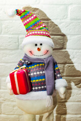 Soft toy funny cheerful smiling snowman in winter knitted hat with carrot nose. Happy New Year. Christmas Eve. christmas decorations.