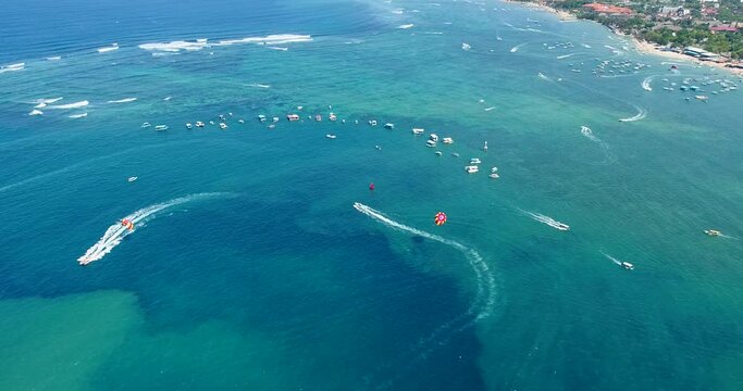 Aerial shot of parasailing boats going over turquoise water