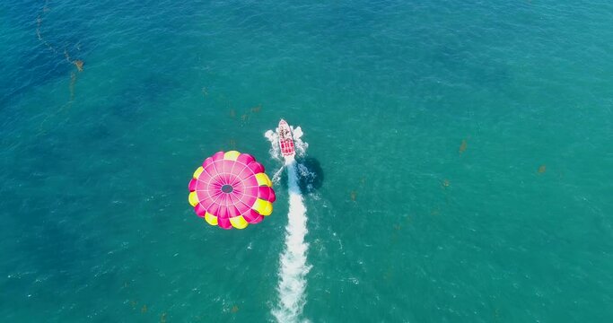 Aerial shot of a parasailing boat going over turquoise water