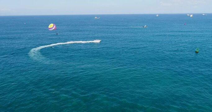 Aerial shot of a parasailing boat going over turquoise water