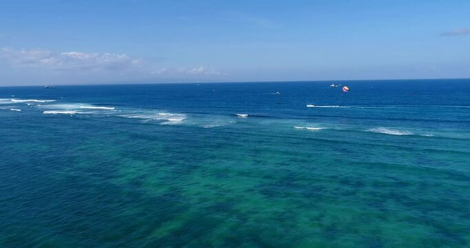 Aerial shot of a parasailing boat going over turquoise water
