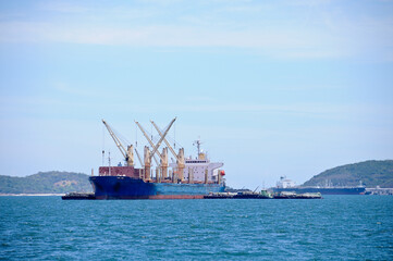 Big ogistic transportation ship with cranes to move cargos around floating in the ocean on sunny day